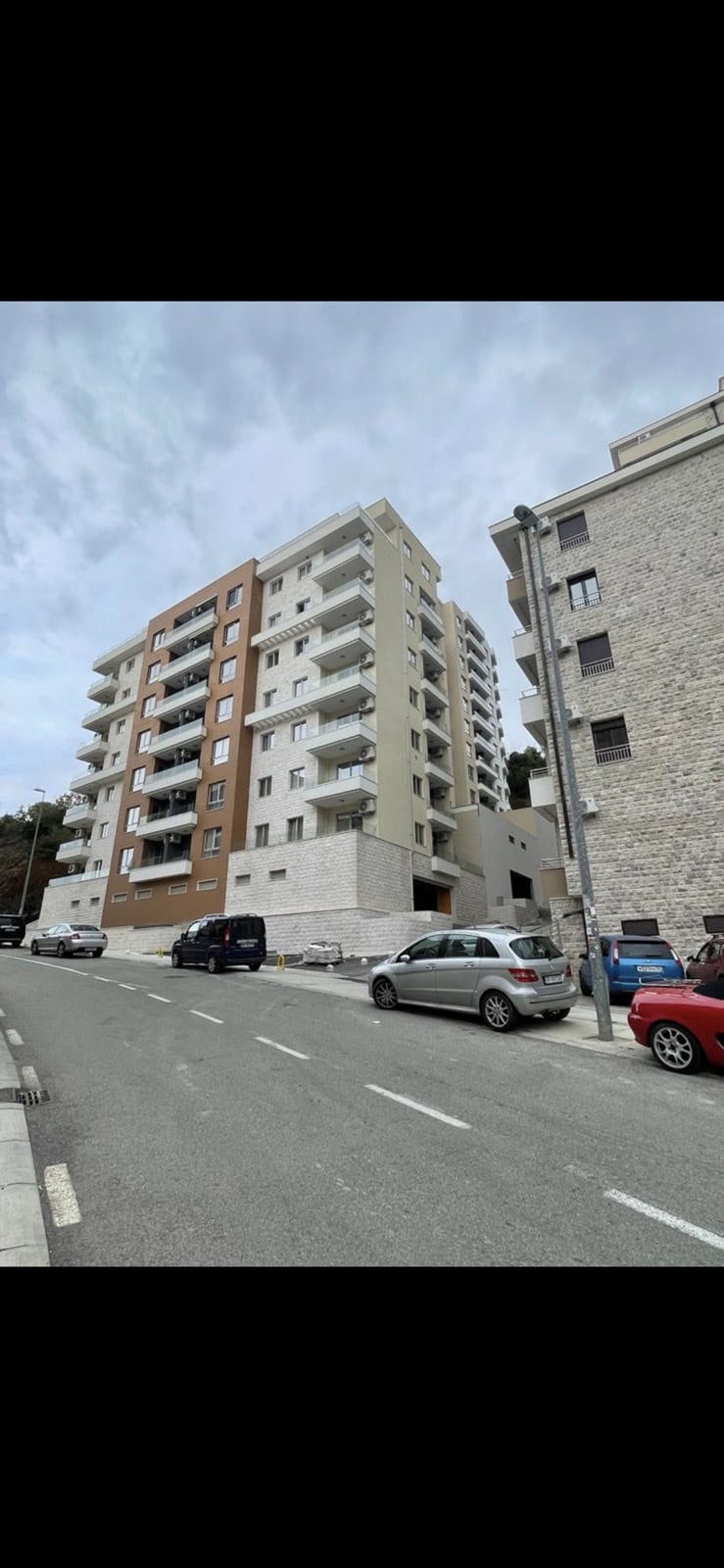 Modern apartment building with balconies in Bečići, Montenegro, street view of the building facade.