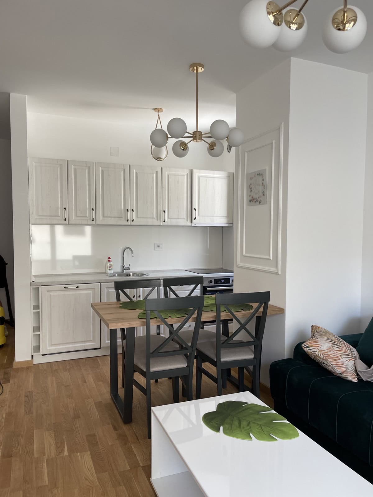 Modern kitchen-living room in an apartment in Bečići, Montenegro: light-colored cabinetry, dining area, and stylish lighting.
