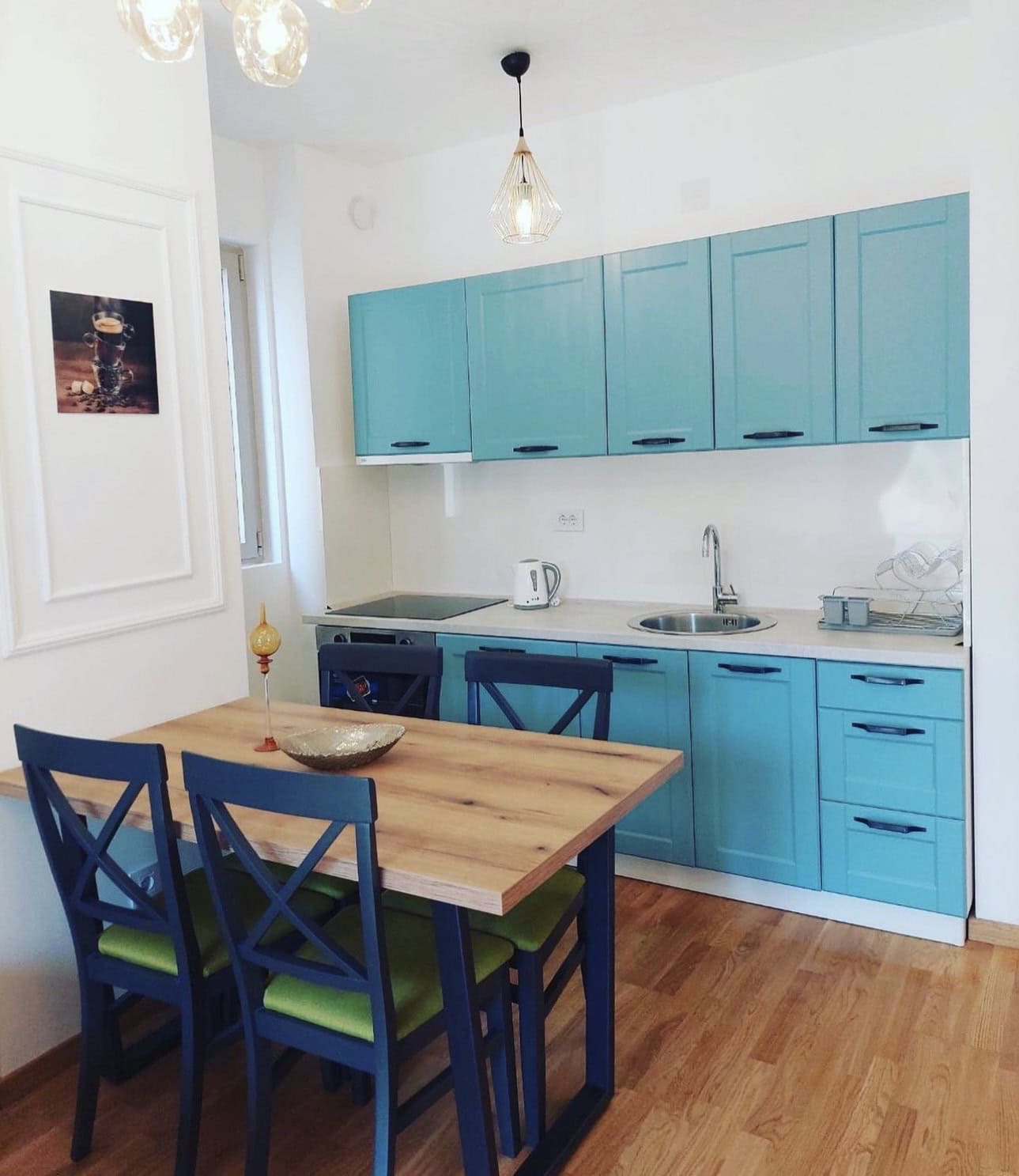 Modern kitchen with a turquoise cabinet set and dining area in an apartment, Bečići, Montenegro.