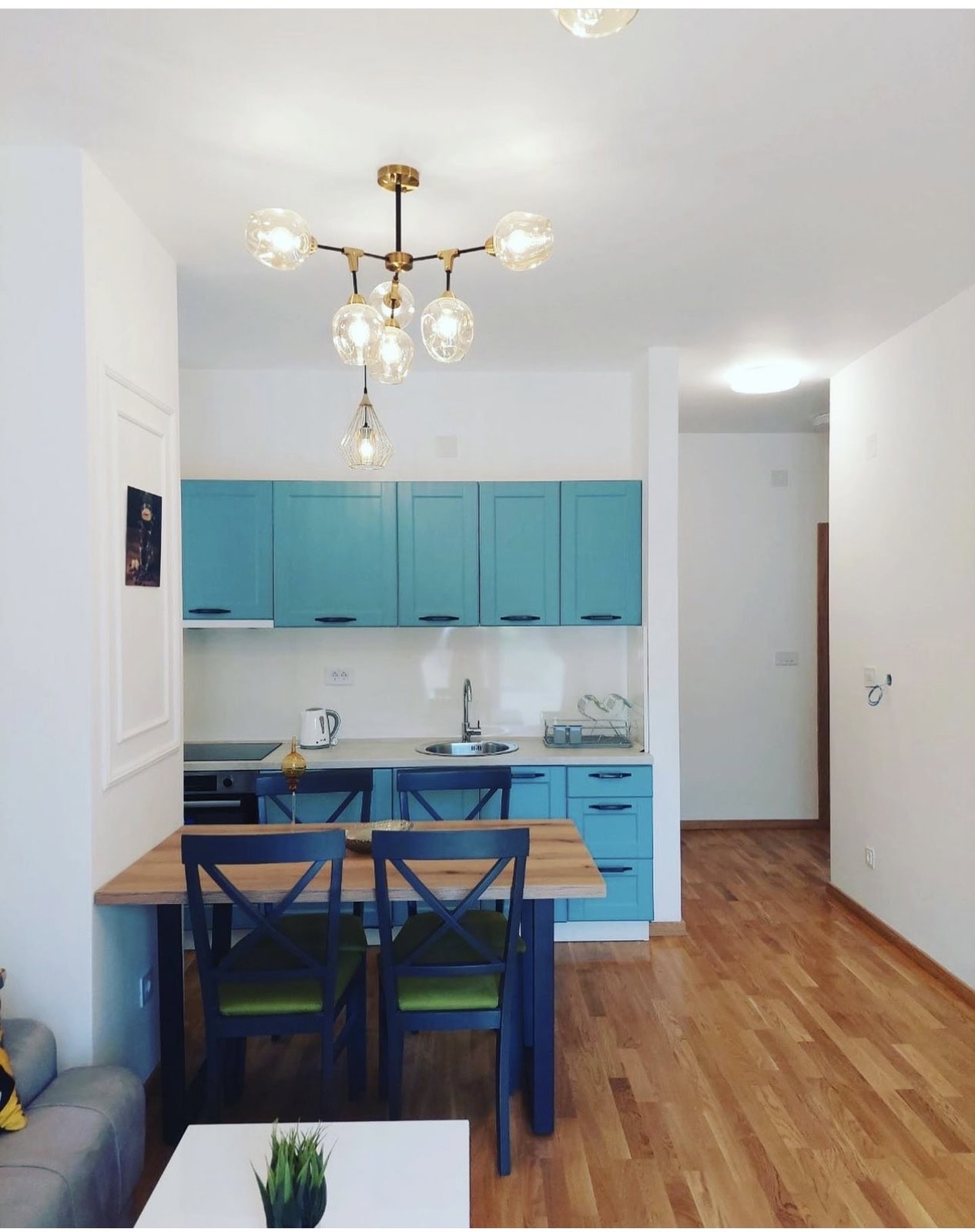 Modern kitchen with a turquoise cabinet set and dining area in an apartment in Bečići, Montenegro.