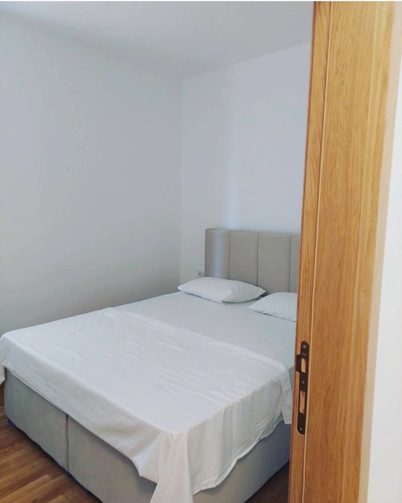 Bright bedroom with a double bed in an apartment in Becici, Montenegro. Modern interior, wooden floor.