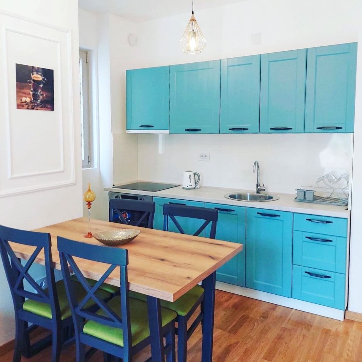 Modern kitchen with a turquoise cabinet set and dining area in an apartment, Becici, Montenegro.