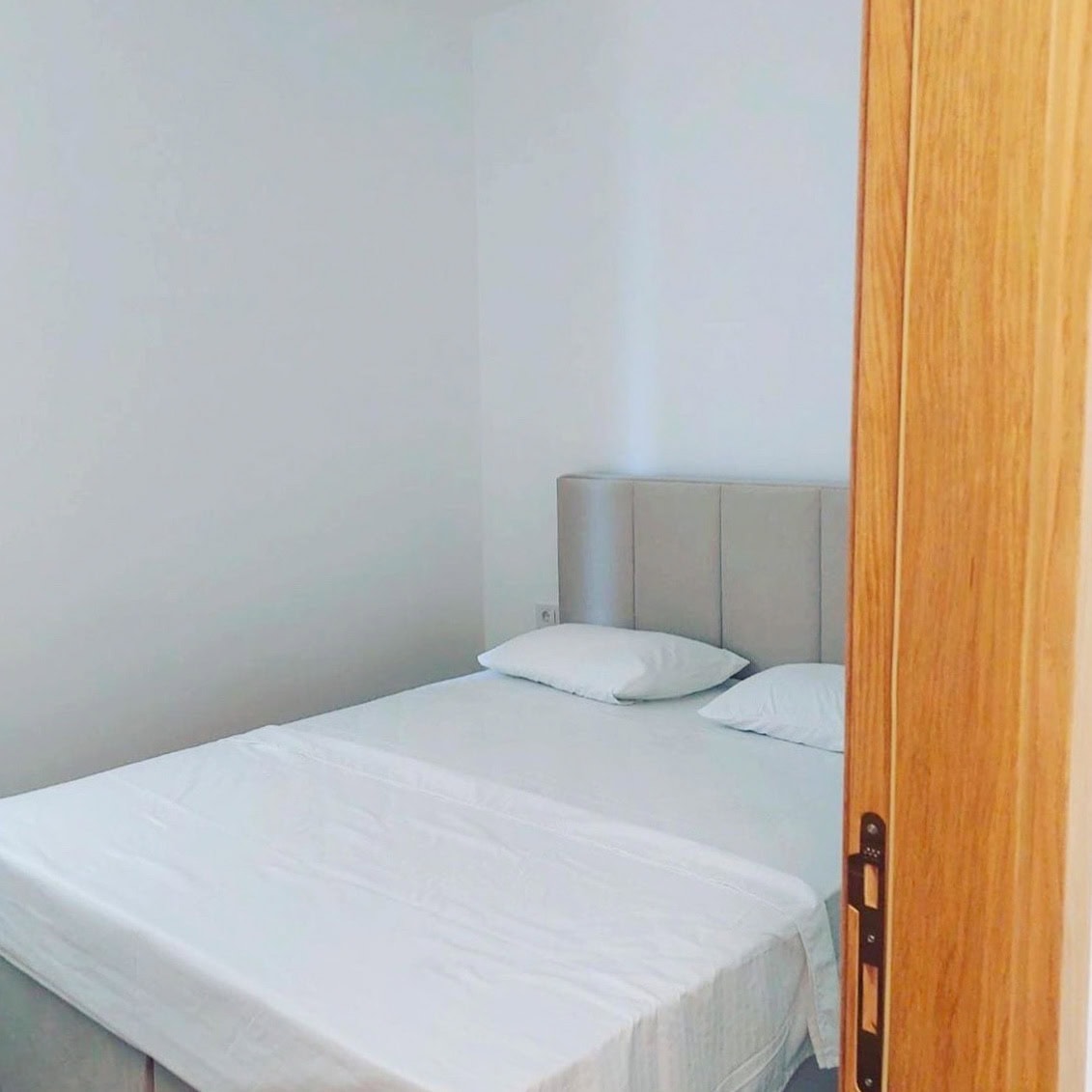 Bright bedroom with a double bed in an apartment in Becici, Montenegro, modern interior with white walls.