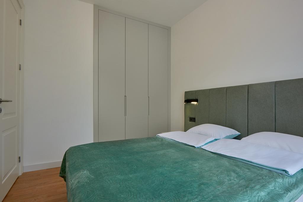 Modern bedroom with a double bed and built-in wardrobe in an apartment, Becici, Montenegro.