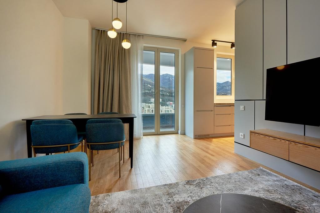 Modern living room in an apartment in Bečići, Montenegro: stylish furniture, parquet flooring, mountain view, and access to the balcony.