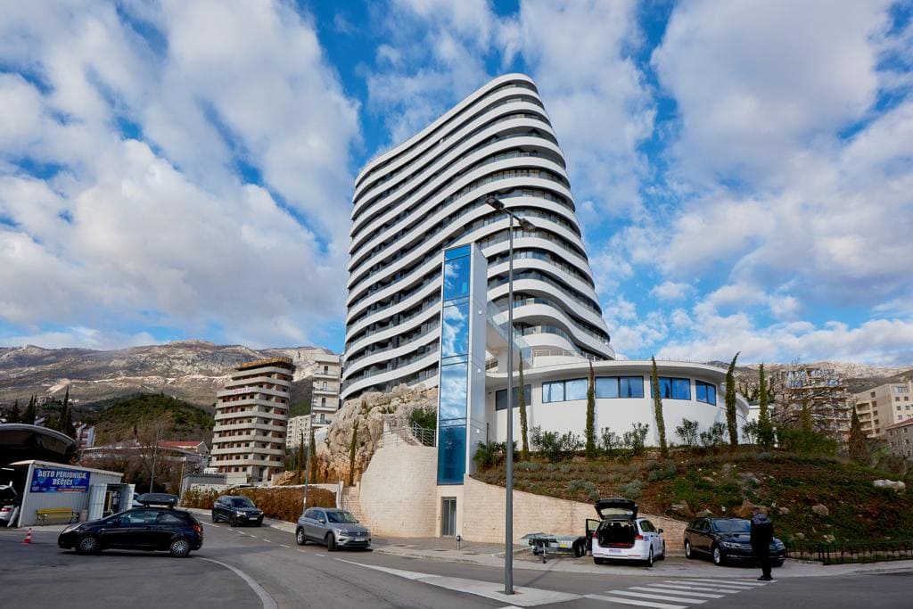 Modern residential complex with panoramic balconies in Bečići, Montenegro — view of the building and surrounding area.