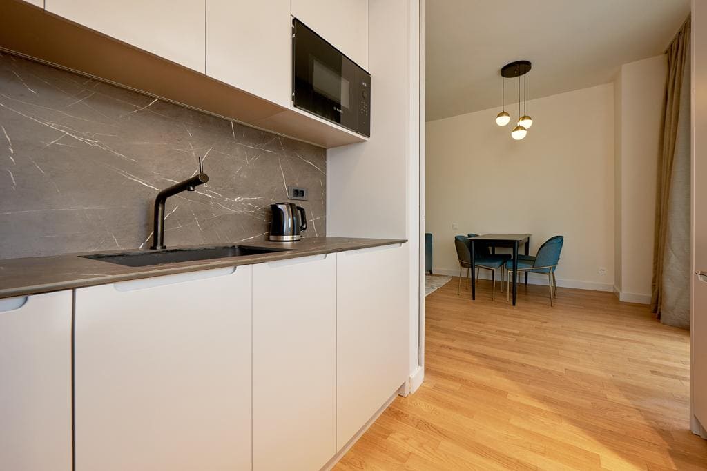 Modern kitchen with marble backsplash and dining area in an apartment, Becici, Montenegro.