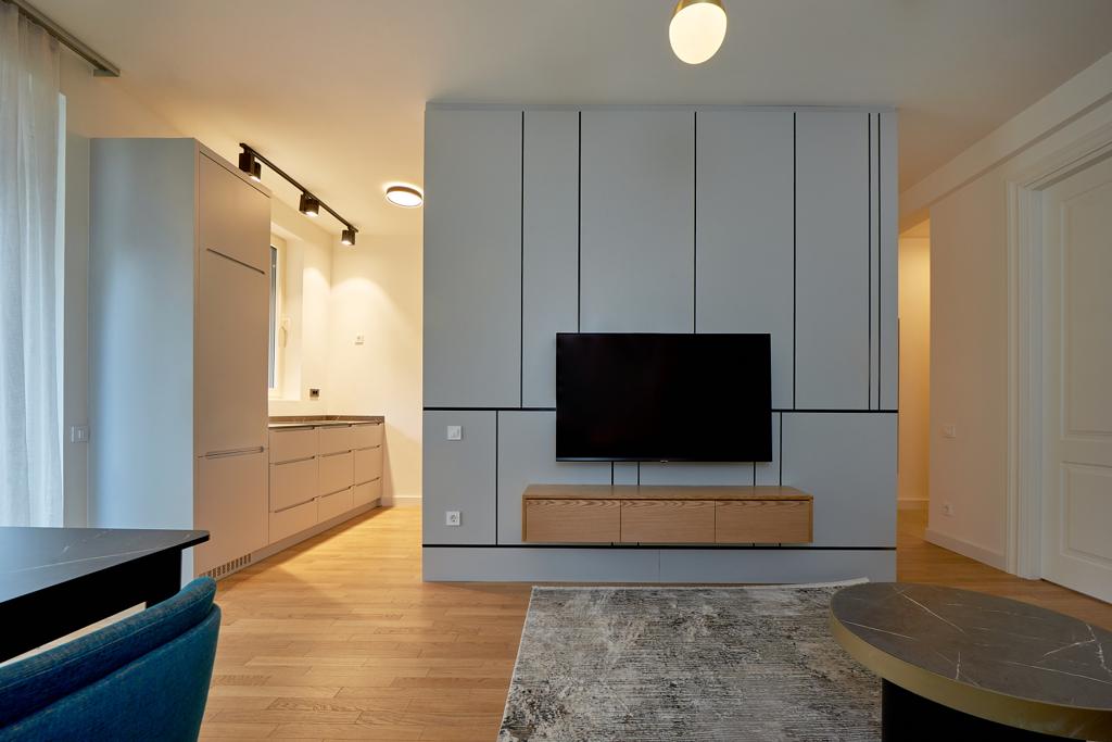 Modern living room with TV area and kitchen in an apartment in Bečići, Montenegro: stylish interior, light furniture, and decor.