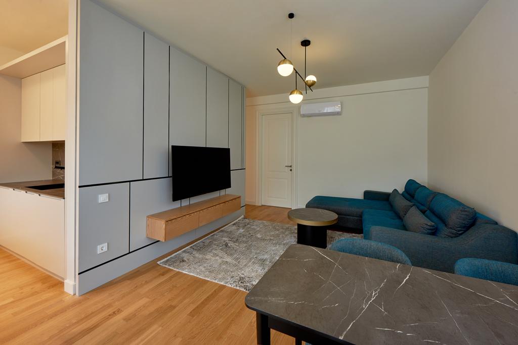 Modern living room in an apartment in Bečići, Montenegro: blue sofa, marble table, and designer TV area.