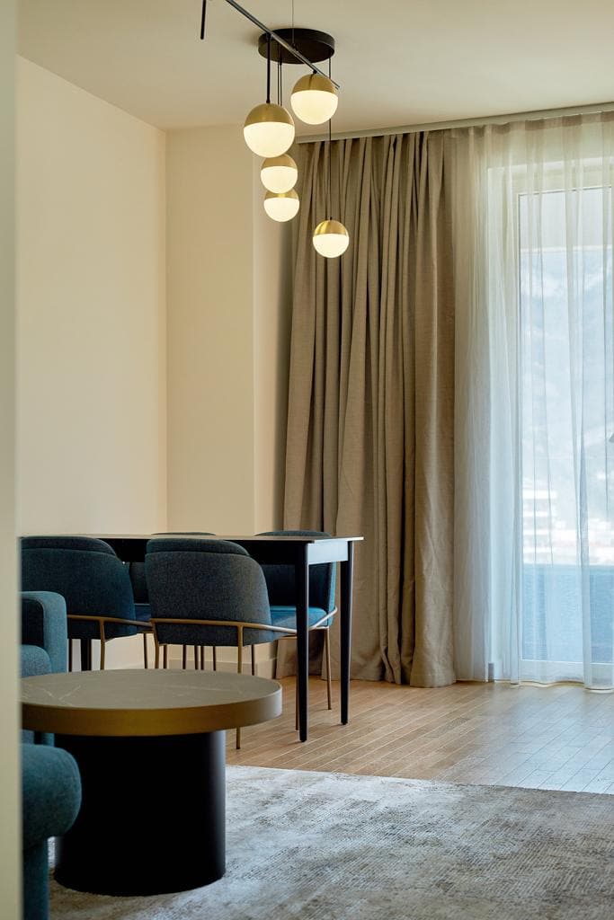 Modern living room with dining area in an apartment, Becici, Montenegro: stylish furniture, panoramic windows, and decor.