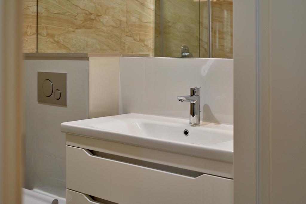 Modern bathroom in an apartment in Bečići, Montenegro: white vanity with sink and onyx-look wall tiles.