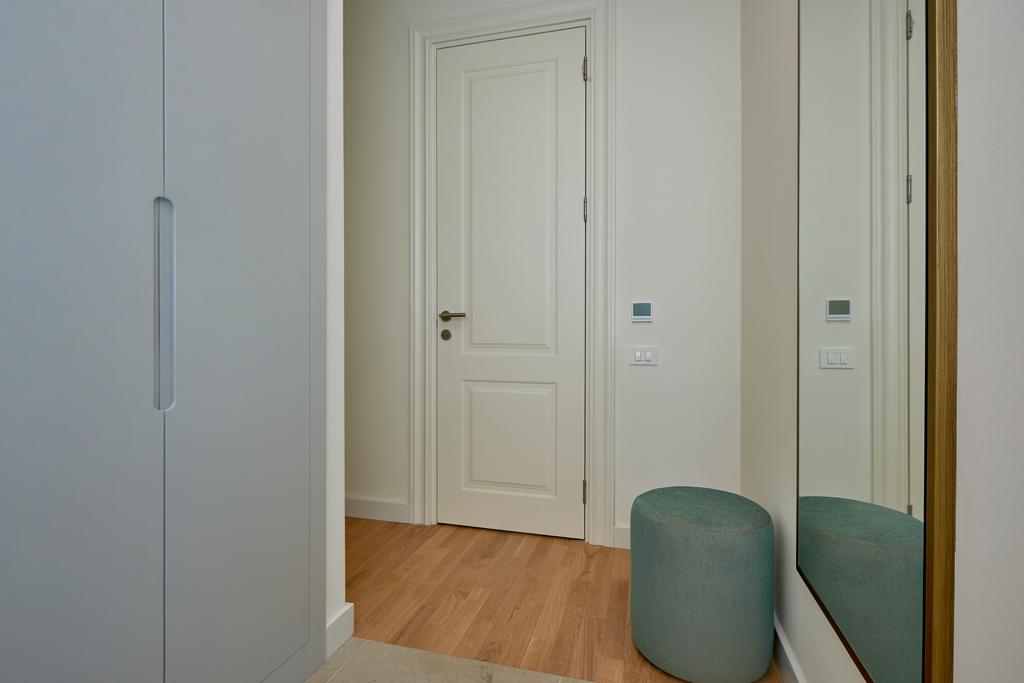 Modern hallway in an apartment, Bečići, Montenegro: built-in wardrobe, light-colored door, and full-length mirror.