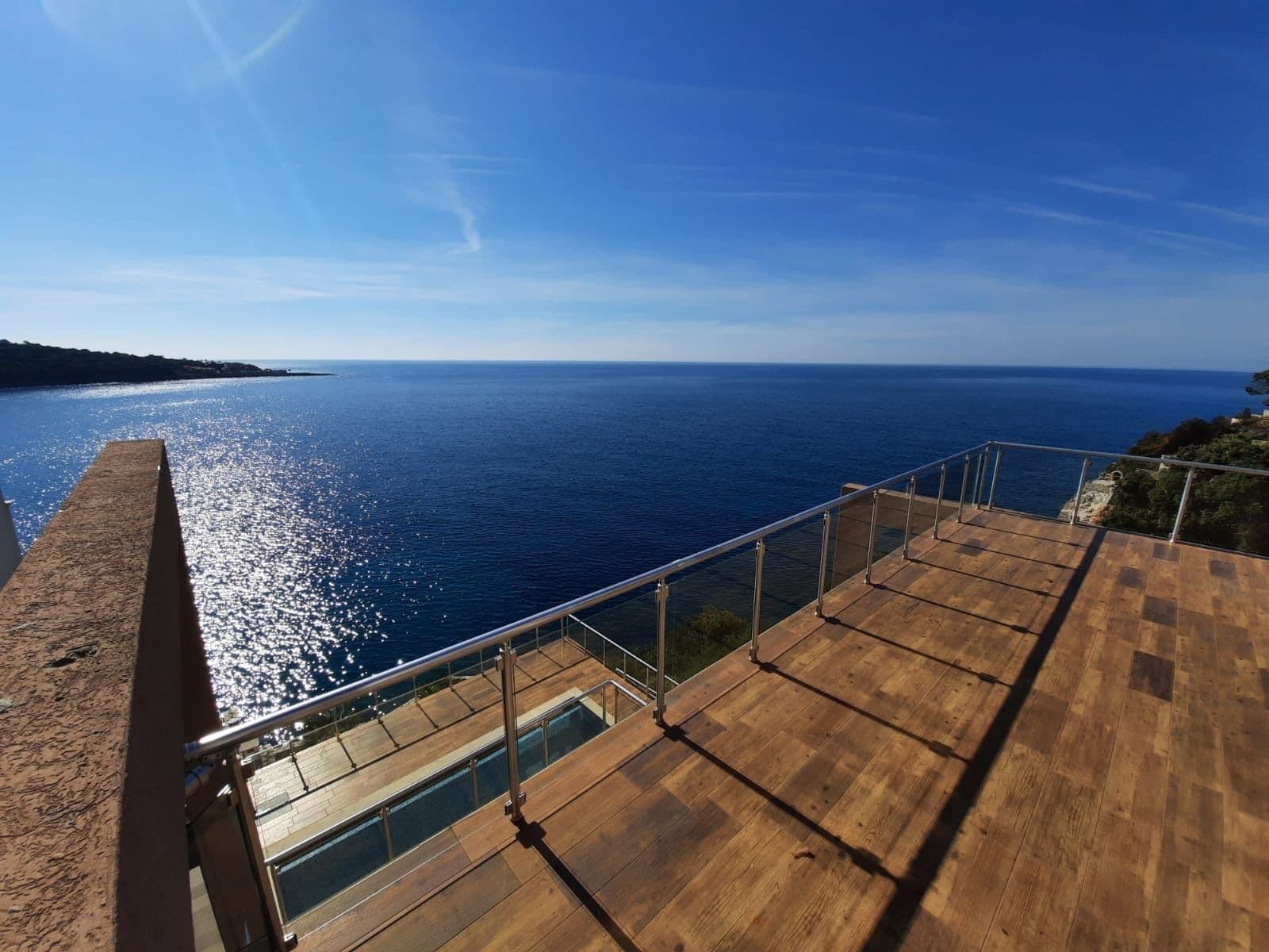 Villa terrace in Kruče, Montenegro: wooden decking, glass railings, and a panoramic view of the Adriatic Sea.