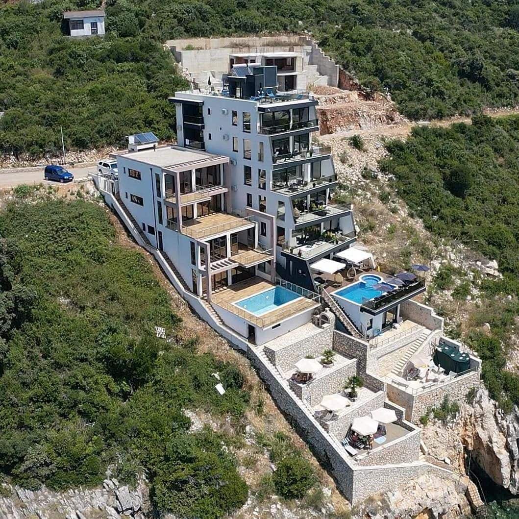 Modern villa with swimming pools and terraces on a cliff in Kruče, Montenegro: view of a luxury residential complex by the sea.