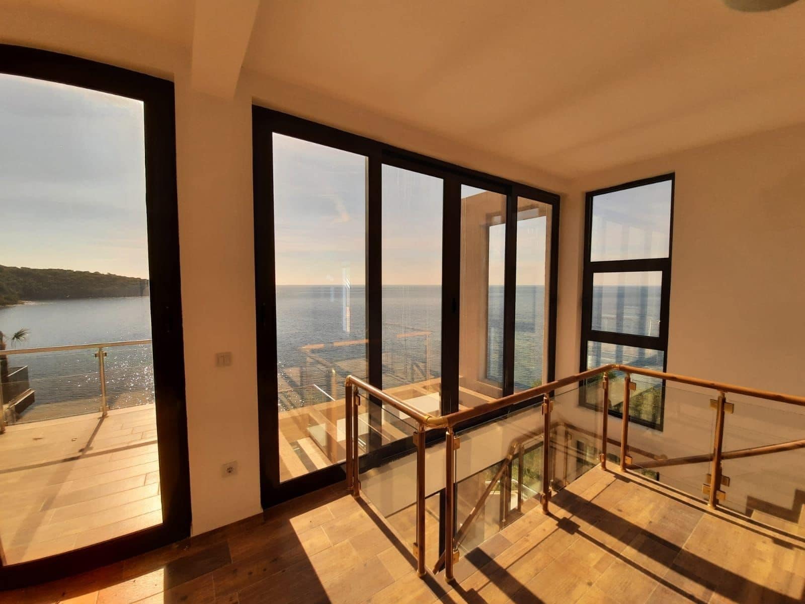 Living room with panoramic windows and sea views in a villa, Dobra Voda, Montenegro: modern interior, terrace, and staircase.