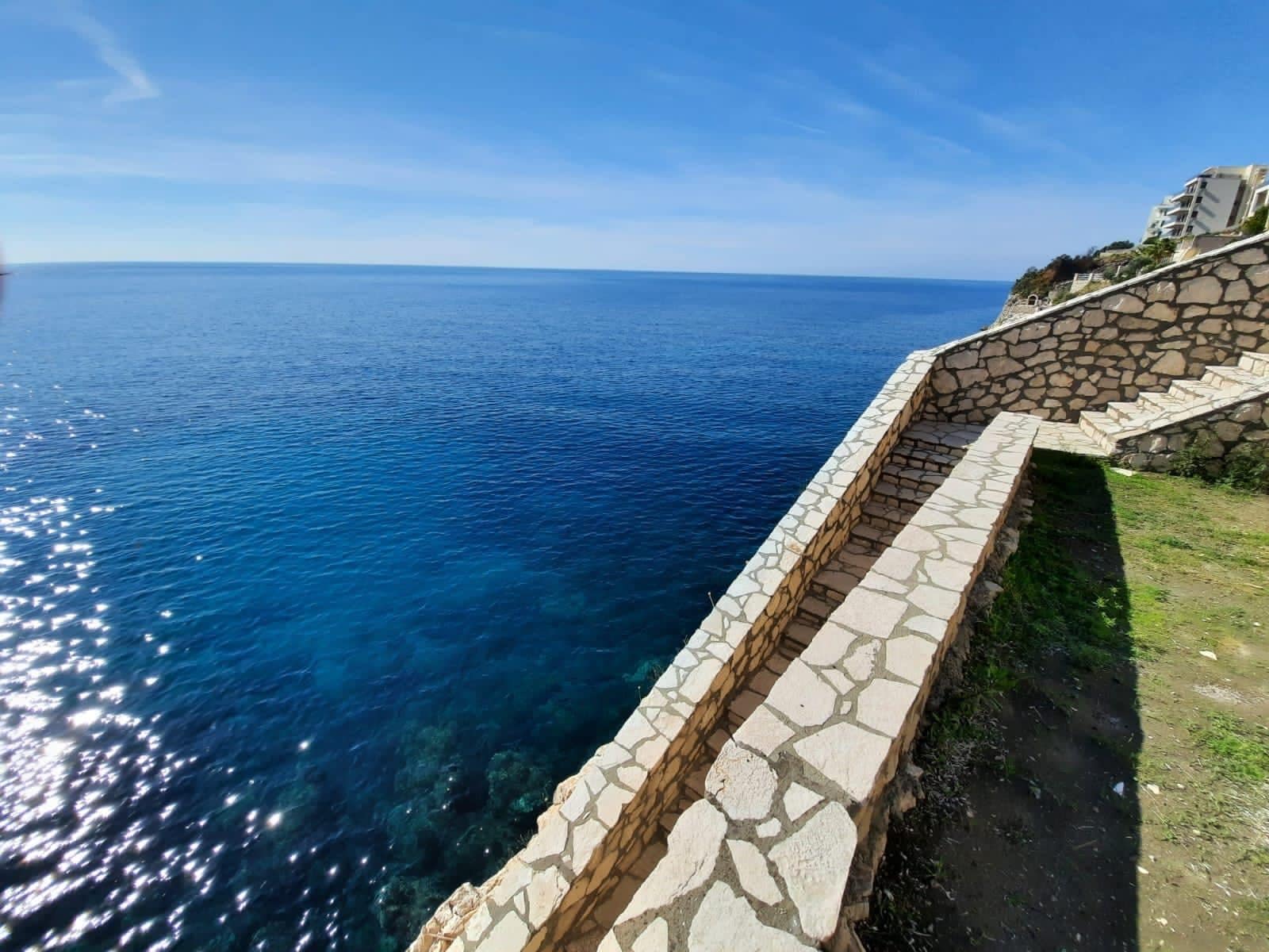 Stone staircase leading to the sea at a villa in Dobra Voda, Kruče, Montenegro, with a panoramic view of the Adriatic coast.