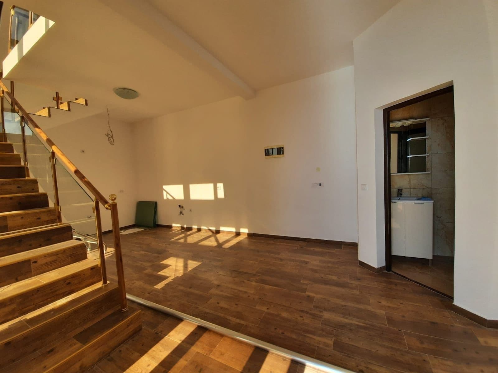 Living room with a wooden staircase and light-toned finishes in a villa in Dobra Voda, Montenegro. Interior view including a bathroom.
