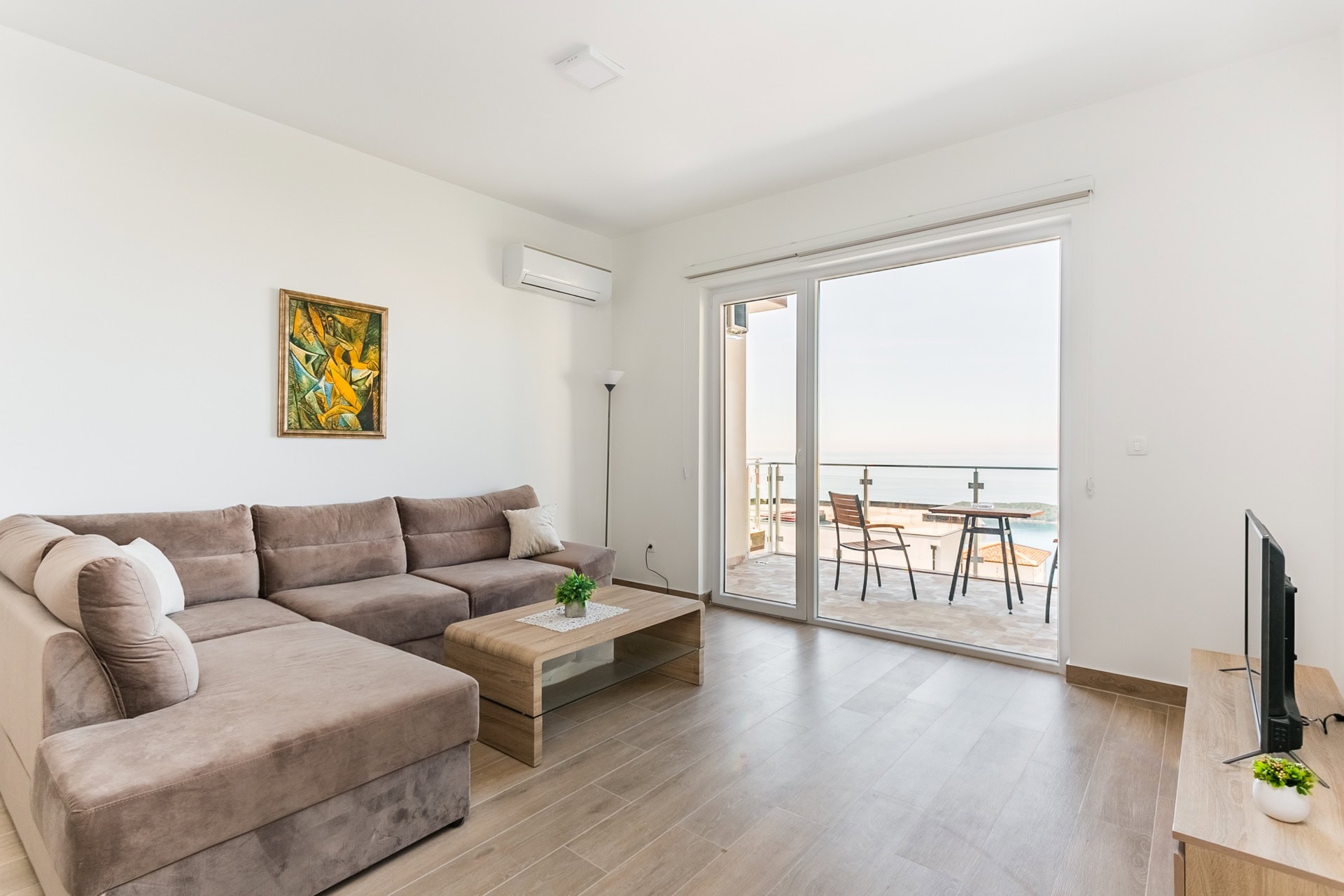 Living room with an L-shaped sofa and access to a terrace with sea view in an apartment, Seoce, Budva, Montenegro.