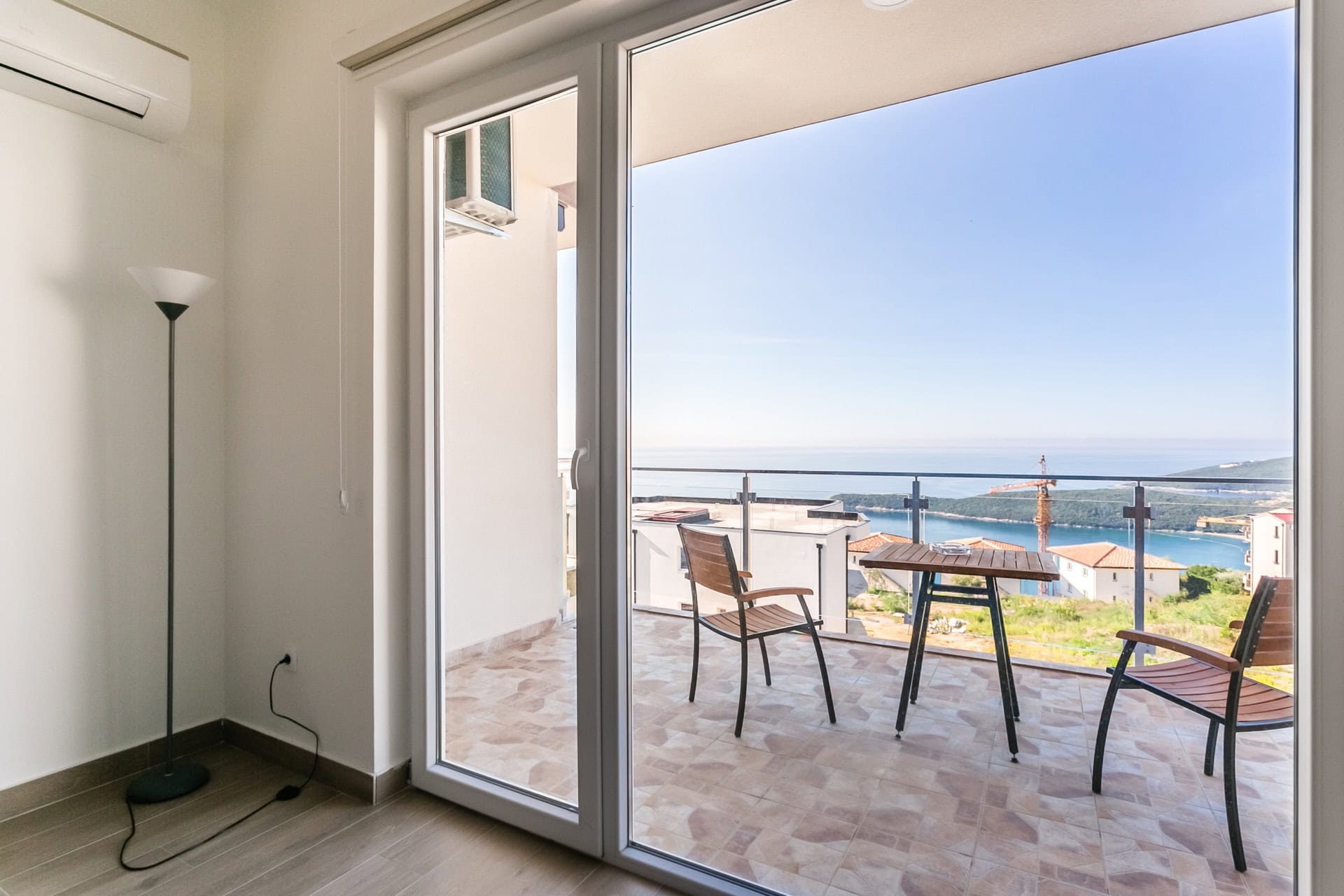 Balcony with furniture and panoramic sea view in the apartment, Seoce, Budva, Montenegro. Modern interior with access to the terrace.