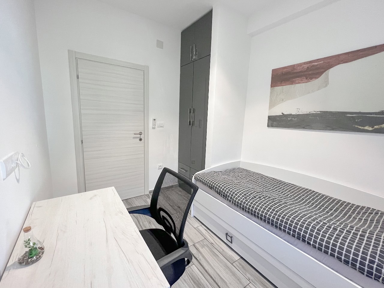 Modern bedroom with a workspace in an apartment, Tivat, Montenegro: bed, desk, and built-in wardrobe.