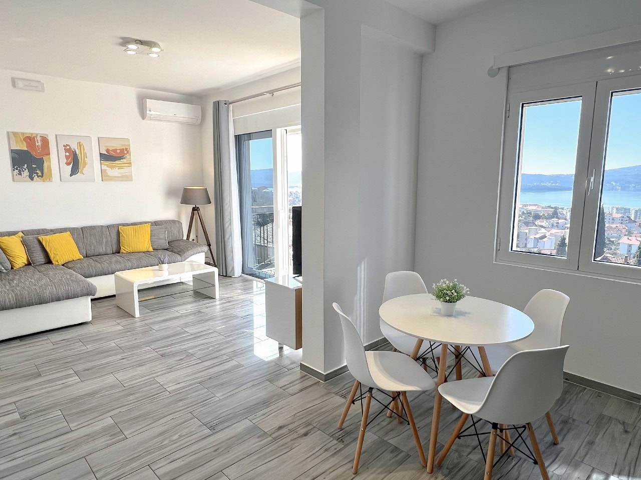 Bright living room with dining area in an apartment in Tivat, Montenegro, with panoramic sea views and modern furniture.