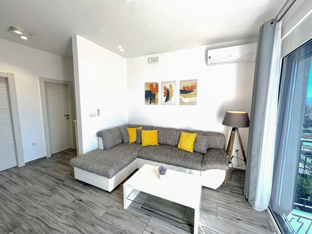 Modern living room with a gray sectional sofa and a white table in an apartment for sale in Tivat, Montenegro.