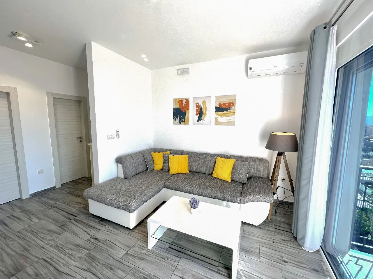 Living room with a gray sectional sofa, yellow pillows, white coffee table, and wall art.