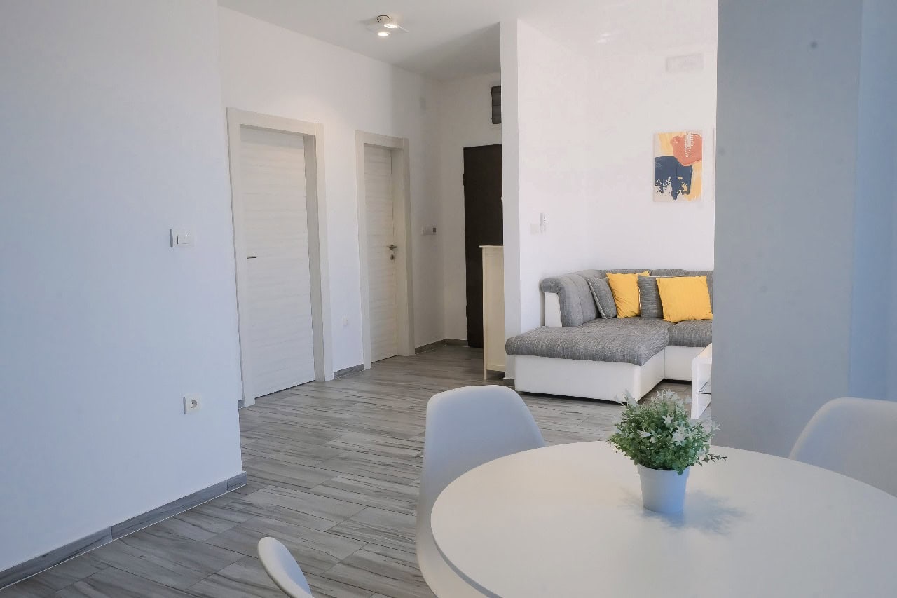 Modern living room with a gray sofa and dining area in an apartment in Tivat, Montenegro. Bright interior.