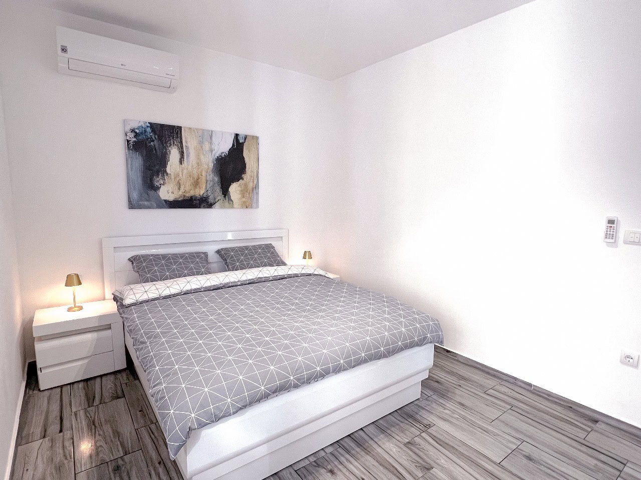 Modern bedroom with a double bed in an apartment in Tivat, Montenegro: bright interior, air conditioning, and tile flooring.