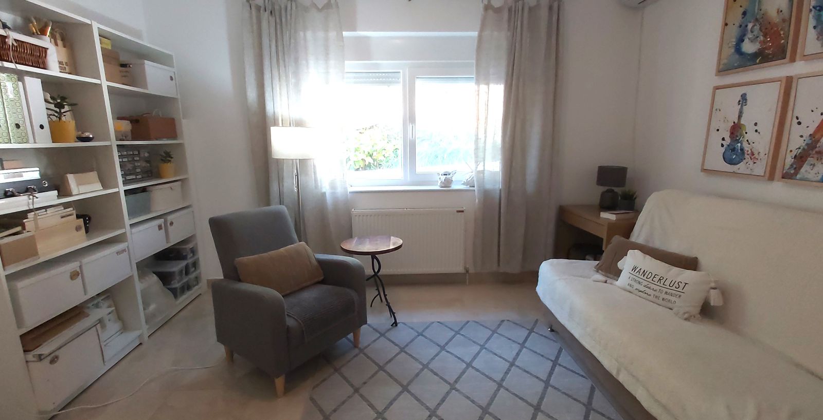 Cozy living room in a house in Krimovica, Montenegro: light-colored furniture, shelving unit, sofa, armchair, and decor in the interior.
