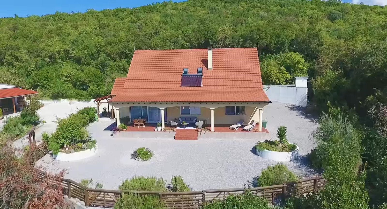 Private house with a tiled roof and terrace in Krimovica, Montenegro: view of the yard with garden furniture and greenery.