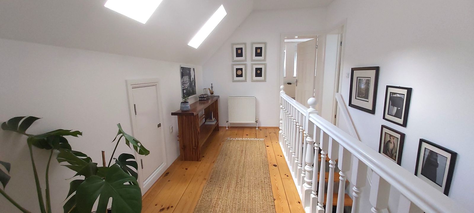 Bright attic hallway in a house, Krymovitsa, Montenegro: wooden floor, skylight windows, and white staircase railings.