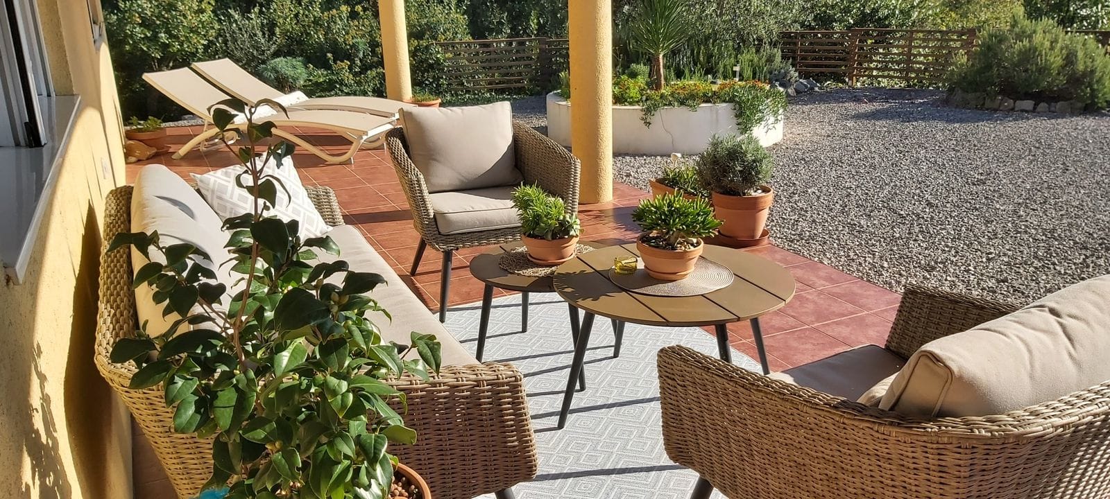 Cozy terrace with wicker furniture and sun loungers at the house in Krumovitsa, Montenegro: view of the landscaped courtyard and garden.