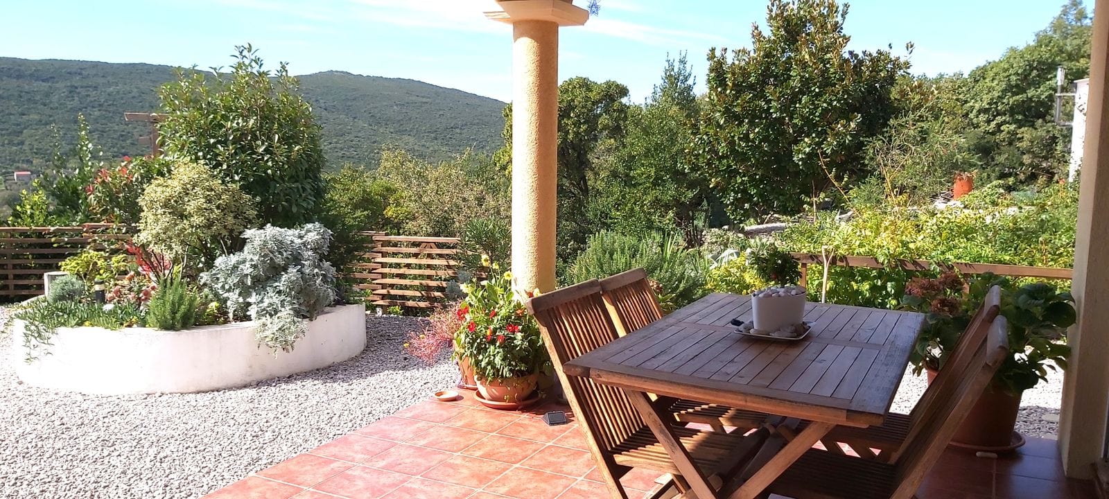 Cozy terrace with wooden furniture and mountain views at the house, Krumovitsa, Montenegro. Landscaped garden.