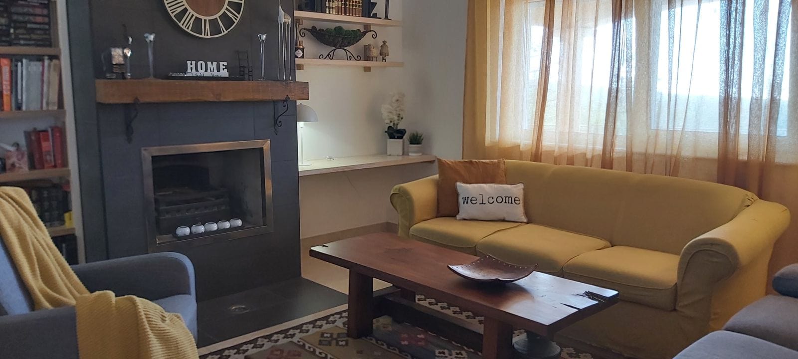 Cozy living room with a fireplace and soft seating in a house, Krymovitsa, Montenegro. Interior with bookshelves and decor.