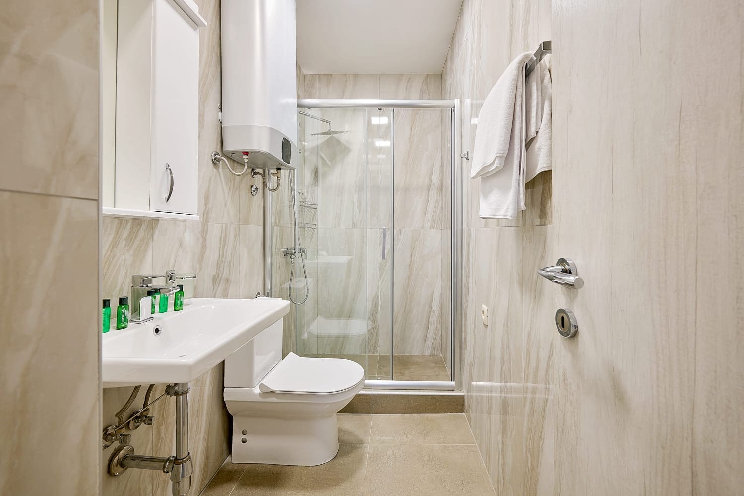 Modern bathroom with a walk-in shower in an apartment, Becici, Montenegro: light-colored tiles and sanitary ware.