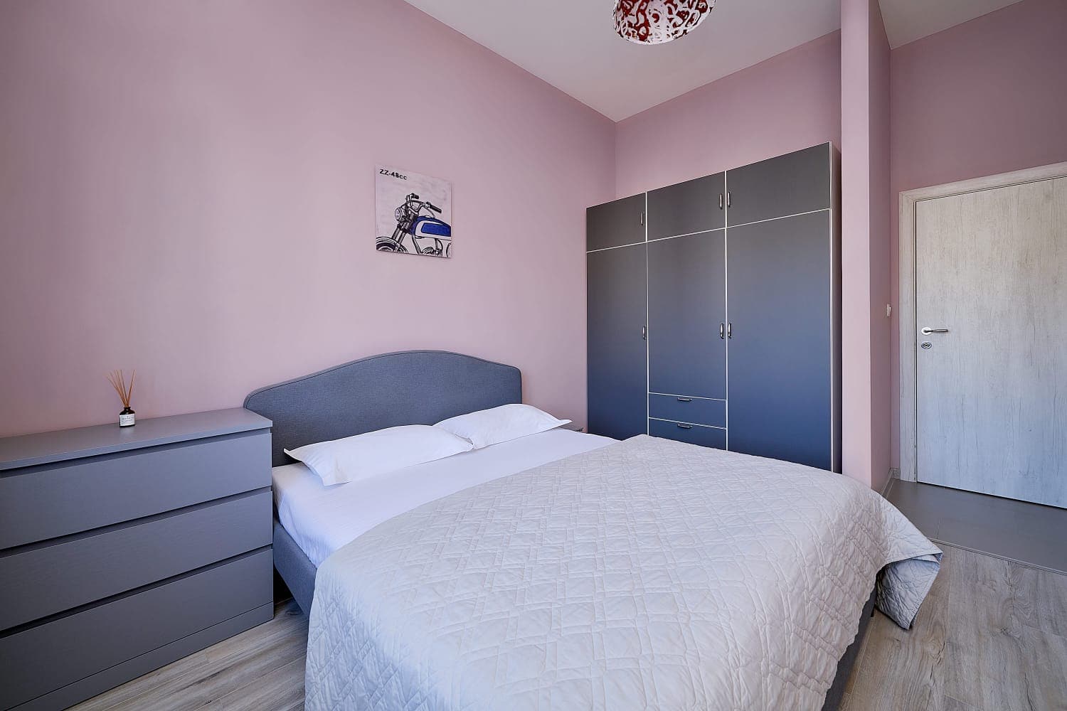 Cozy bedroom with a double bed and a grey wardrobe in an apartment in Bečići, Montenegro. Modern interior.