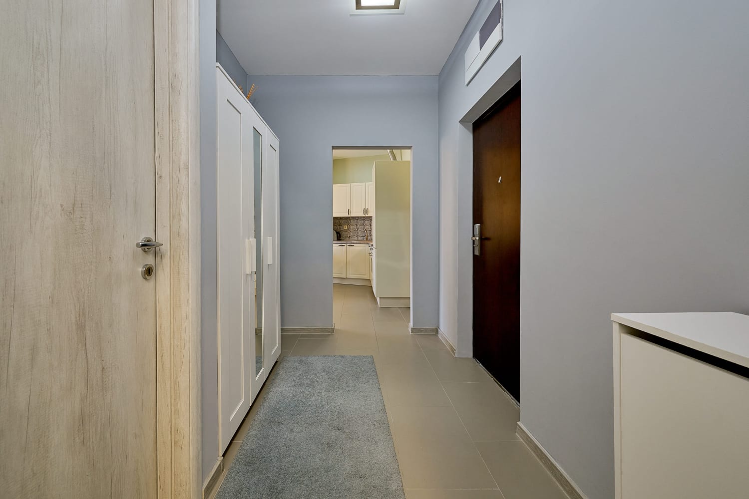Bright hallway in an apartment in Bečići, Montenegro: built-in wardrobe, tiled floor, and a view of the kitchen.