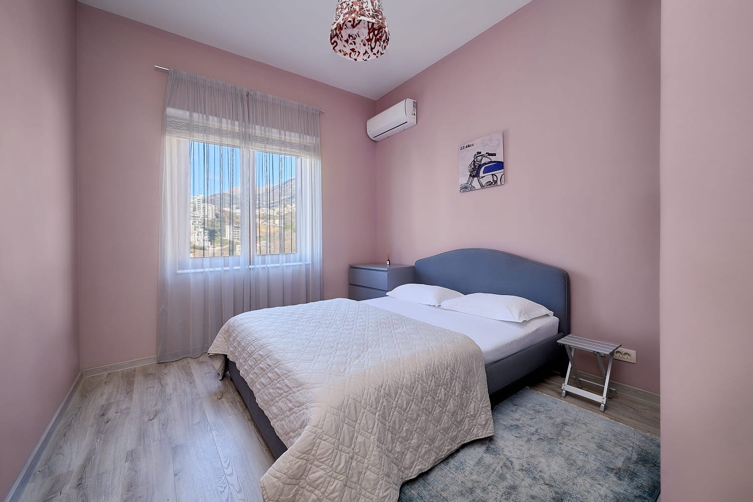 Cozy bedroom with a double bed in an apartment in Bečići, Montenegro: bright interior, mountain view, and air conditioning.