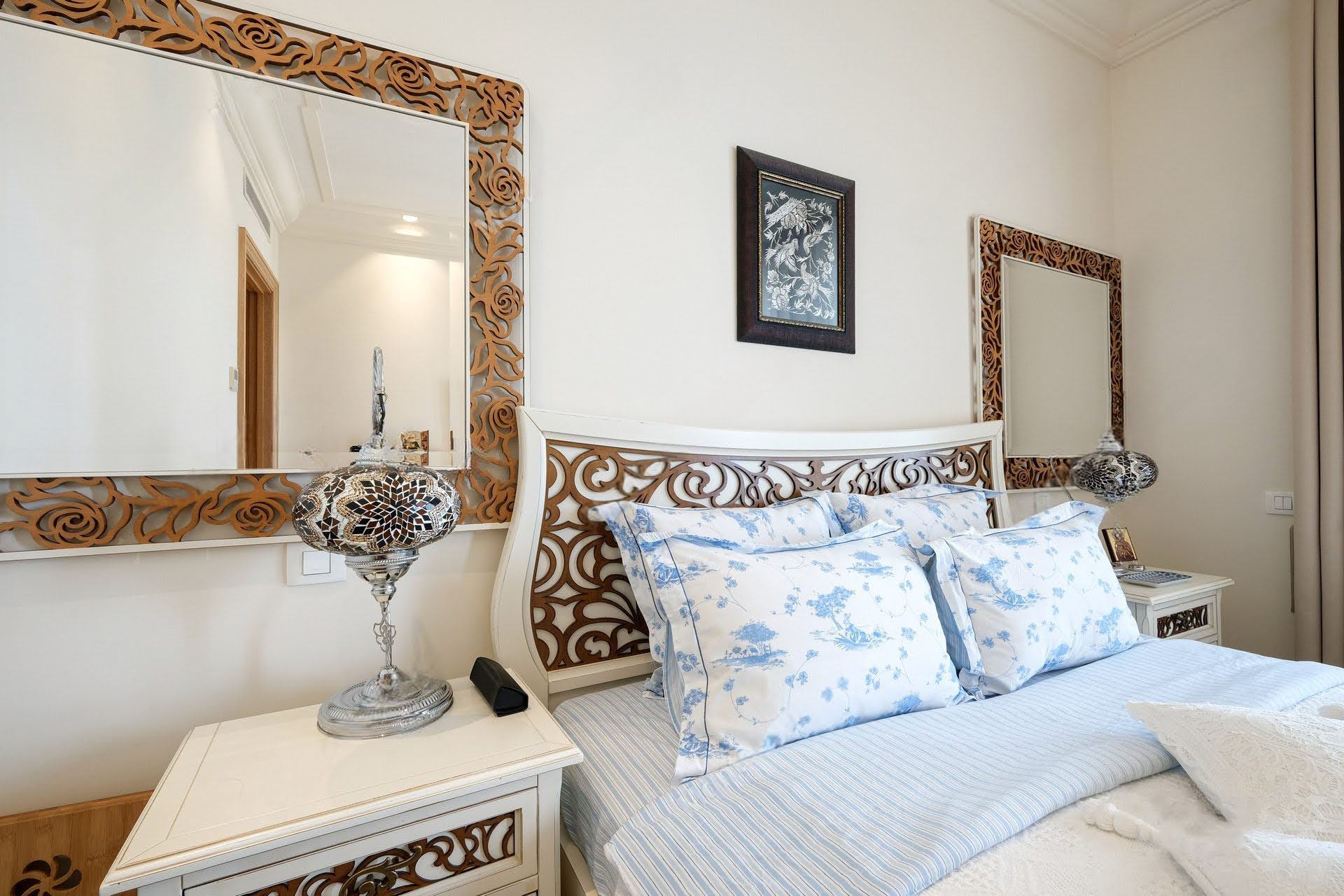 Cozy bedroom in an apartment in Tivat, Montenegro: a double bed with a carved headboard and oriental lamps.