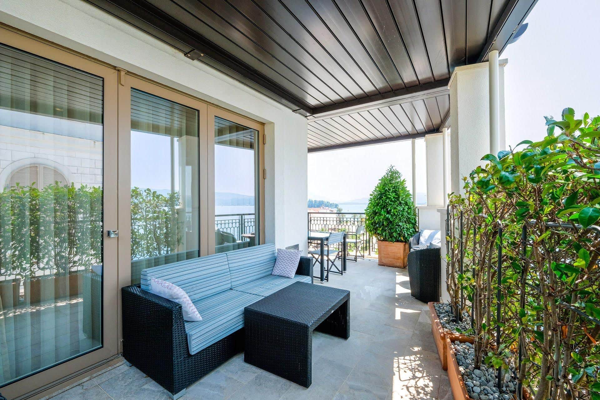 Cozy terrace with wicker furniture and sea view in an apartment in Tivat, Montenegro. Modern balcony with plants.