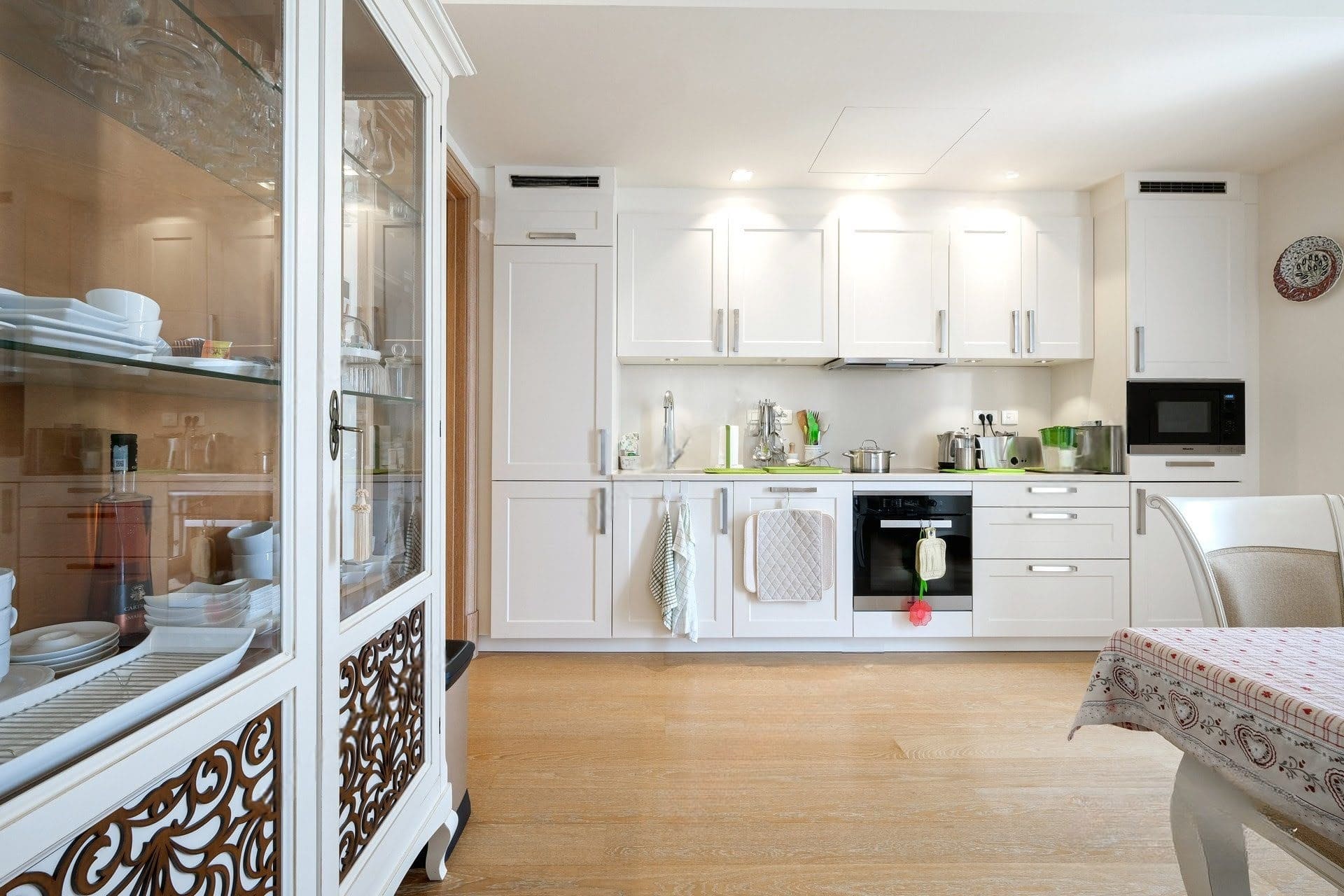 Bright kitchen with white cabinetry and built-in appliances in an apartment in Tivat, Montenegro. Interior with a display cabinet.