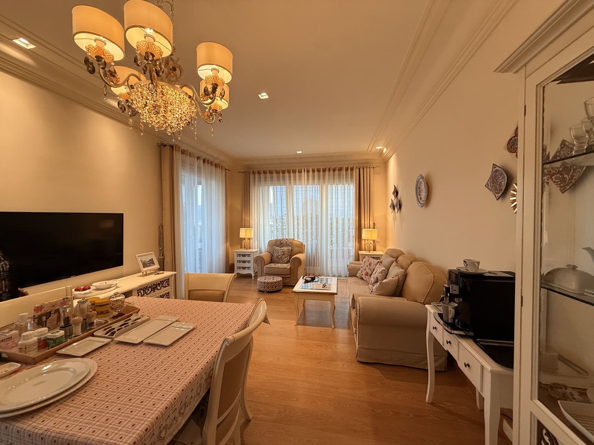 Cozy living room with classic furniture in an apartment in Tivat, Montenegro: dining area, sofa, and crystal chandelier.