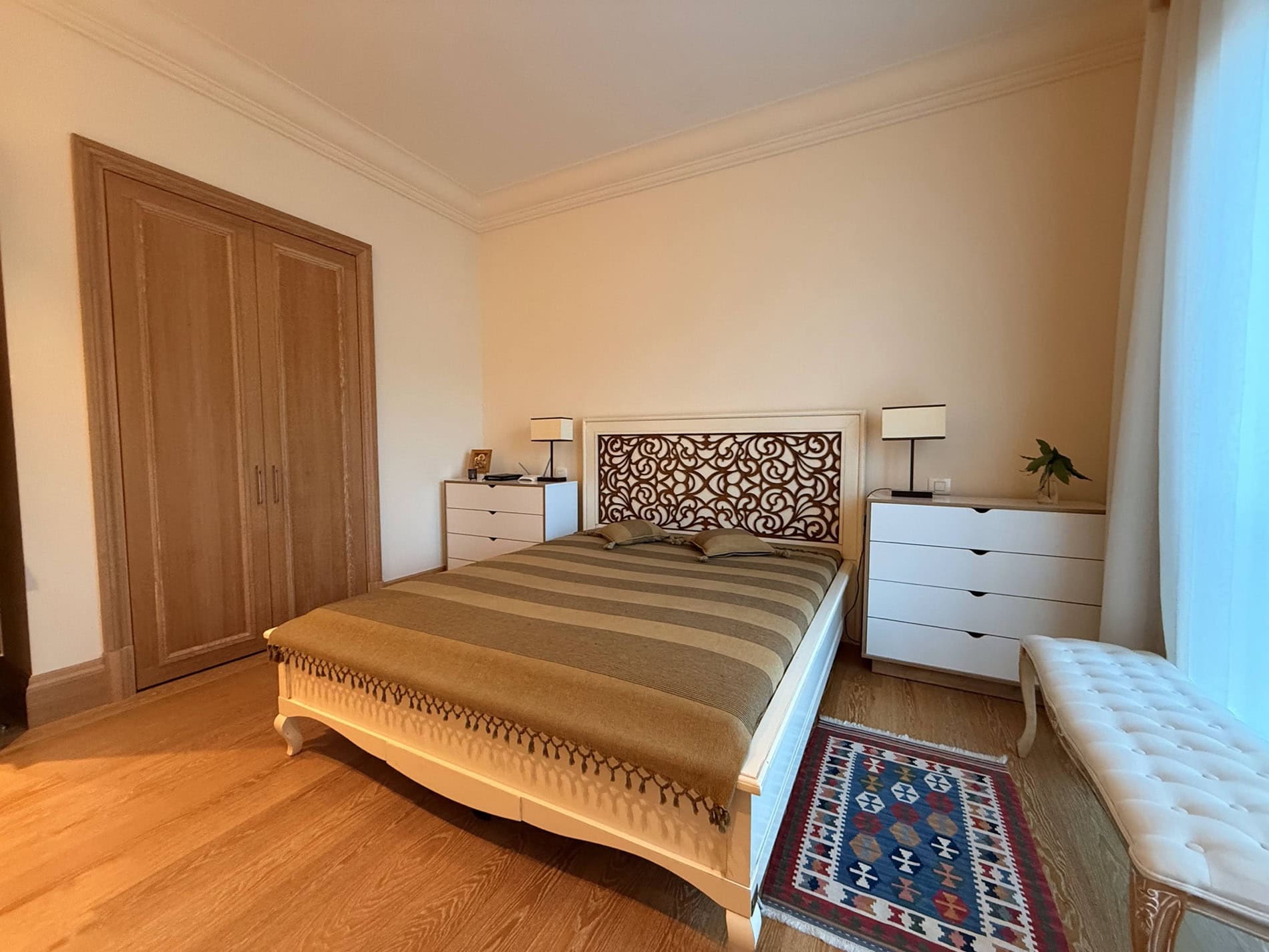 Cozy bedroom with a double bed and a wooden wardrobe in an apartment for sale in Tivat, Montenegro.