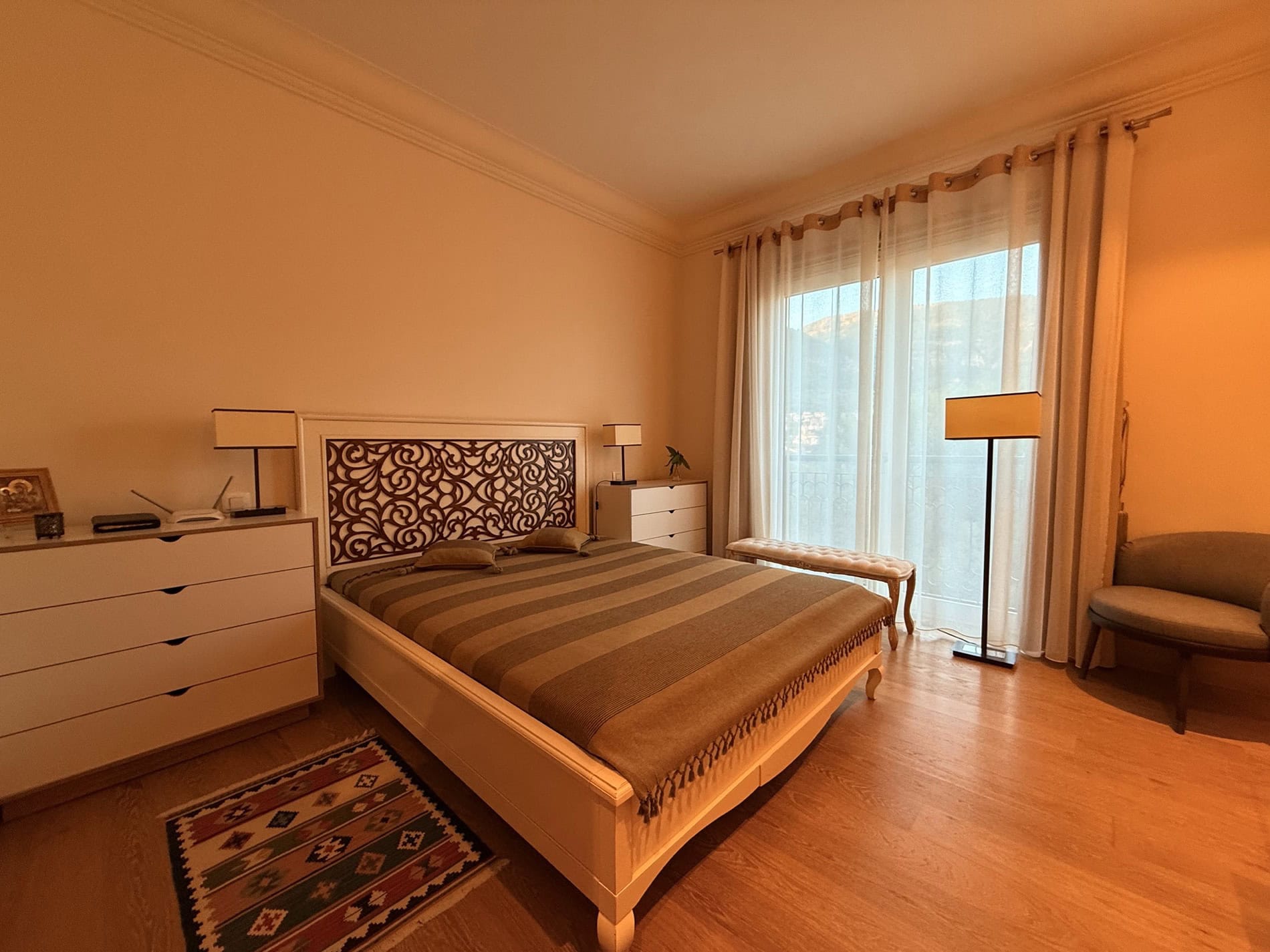 Cozy bedroom with a double bed in an apartment in Tivat, Montenegro: light furniture, parquet flooring, and access to the balcony.