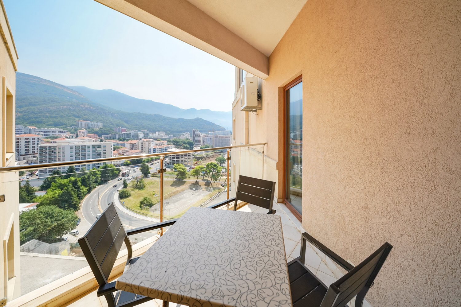 Balcony with furniture and panoramic views of the mountains and the town of Bečići, Montenegro, in apartment #2436