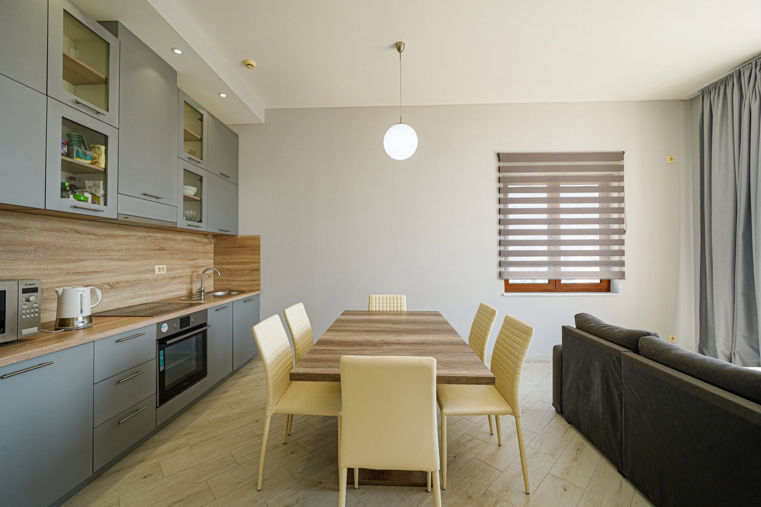 Modern kitchen-living room in an apartment, Becici, Montenegro: grey cabinetry, dining table, and light-toned finishes.