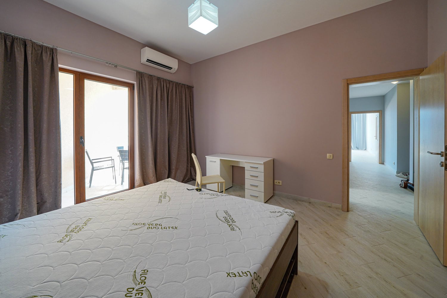 Bedroom in an apartment in Bečići, Montenegro: double bed, desk, balcony access, and bright interior finishes.