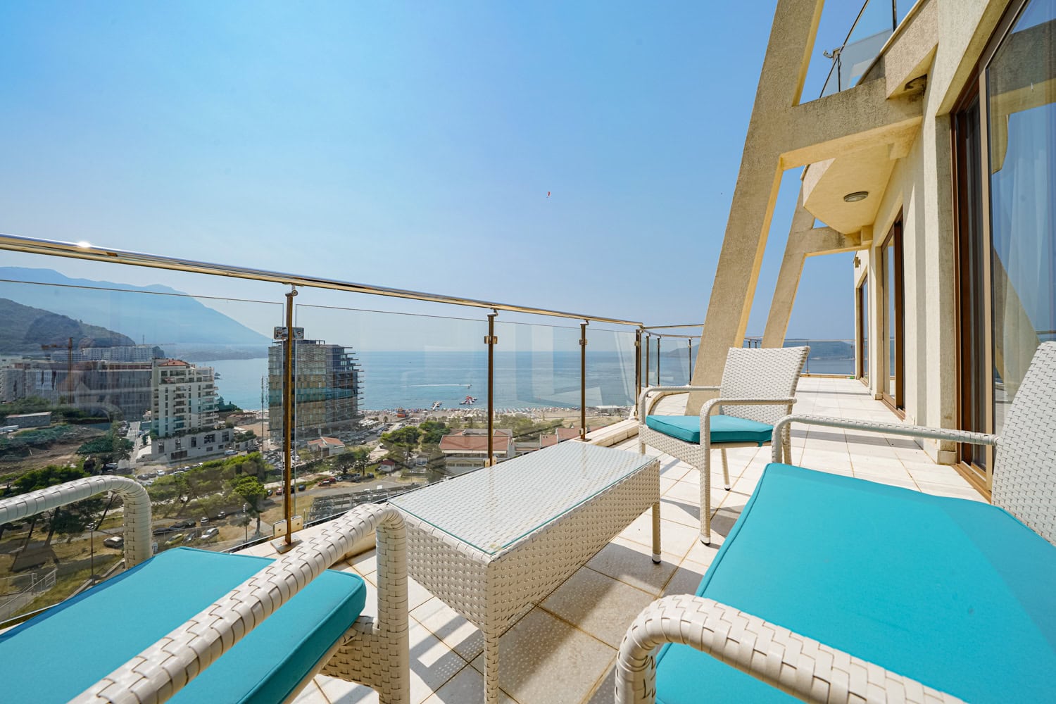 Terrace with wicker furniture and a view of the sea and beach in an apartment in Bečići, Montenegro.