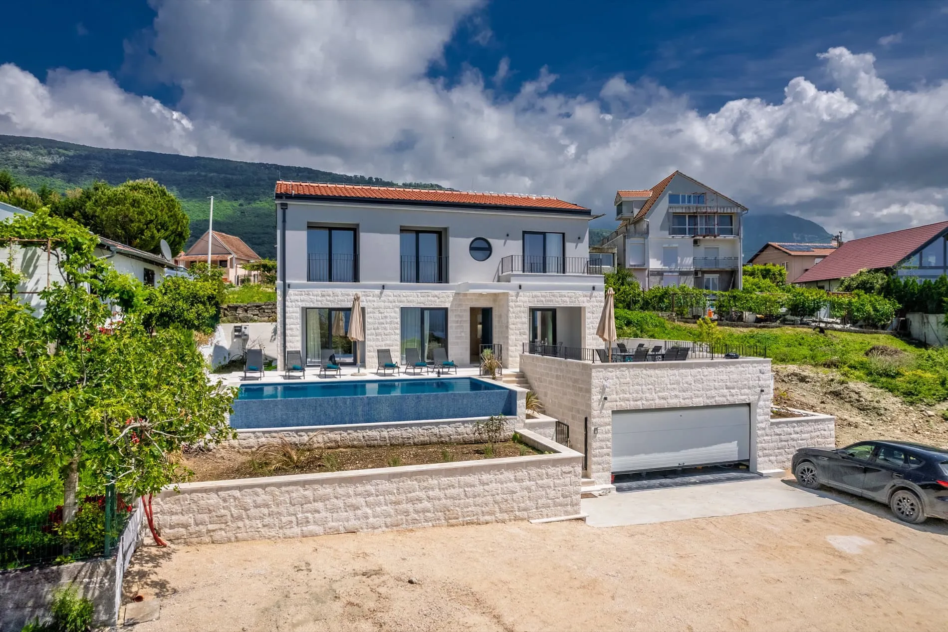 Modern house exterior featuring a blue pool, patio furniture, and garage.
